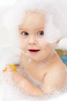 Little baby girl bathing in soapsuds