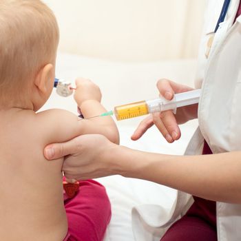 Doctor giving a child a huge injection in arm, shallow DOF