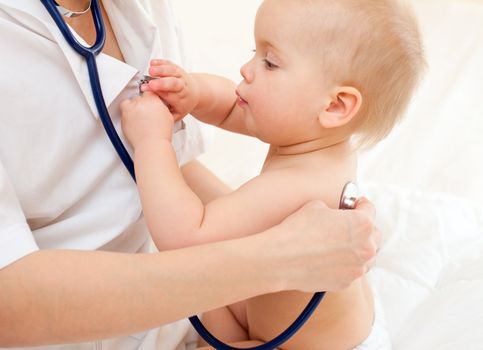 Pediatrician examing little baby girl with stethoscope