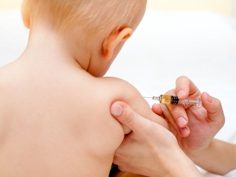 Doctor giving a child an intramuscular injection in arm, shallow DOF