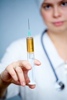 Doctor holding big syringe with yellow liquid, focus on syringe