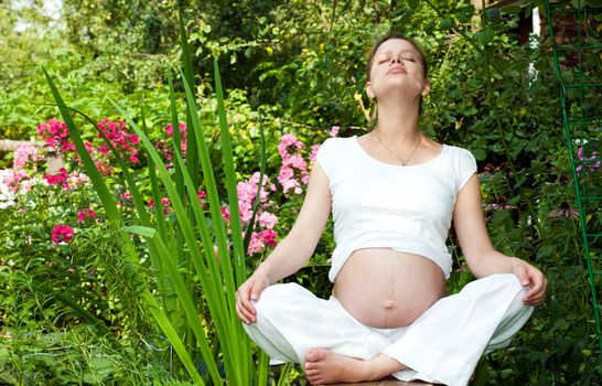Young pregnant woman relaxing in a summer garden