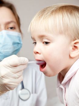 Doctor giving a spoon of syrup to little girl