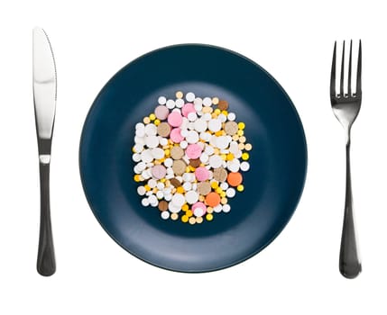Diner plate with pills fork and knife on white background