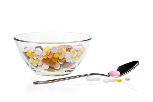 Spoon with purple tablet near glass bowl filled with tablets