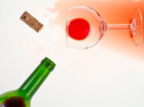 Bottle, cork and glass on red wine spill