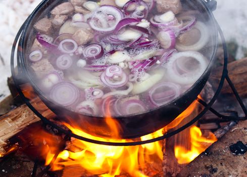 Cooking Chorba soup in cauldron on fire