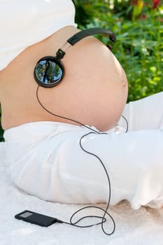 Headphones on a pregnant woman's belly