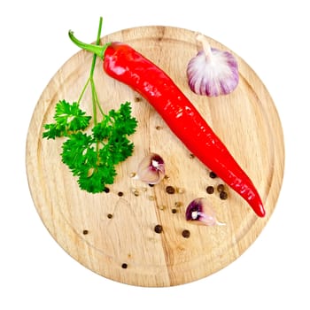 Hot red pepper, garlic, parsley, peppercorns and mustard on a circular wooden board isolated on white background