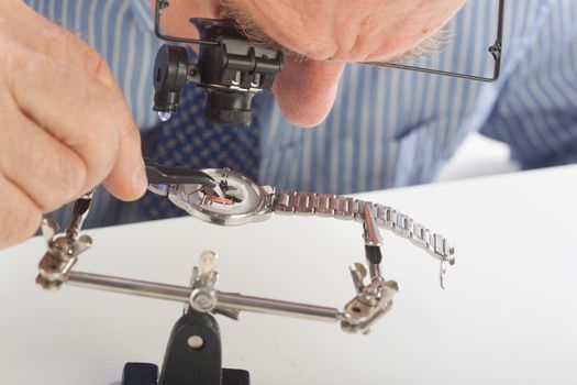 An older man wearing a shirt and tie, repairing a watch.