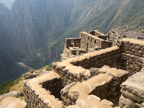 Morning views of Machu Picchu showing stone walls of buildings above valley