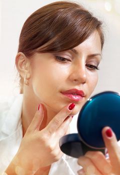 beautiful woman smartens up in front of compact mirror