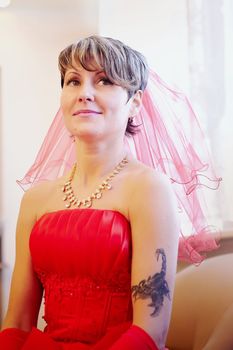 Portrait of the bride in a red dress on a light background