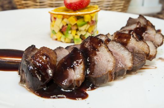 baked meat with sauce and garnish on a plate in a restaurant