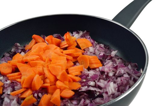 Onions and carrots in a frying pan. Isolated on white.