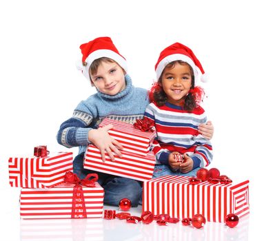 Smiling little mullato girl and her brother in Santa's hat with gift box, isolated on white