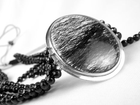 A beautiful designer necklace made of a silver pendant and black crystals.                               