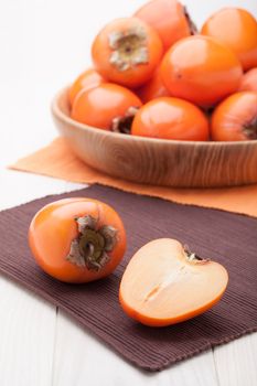 Fresh exotic tropic ripe juicy orange fruits  persimmon Diospyros served in wooden plate on table