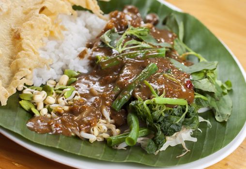 Nasi pecel is a Javanese rice dish served with mix vegetables and peanut sauce