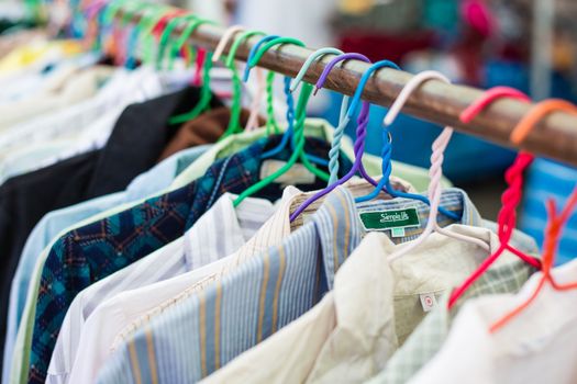 Old shirt hanging on plastic hangers in second hand maket