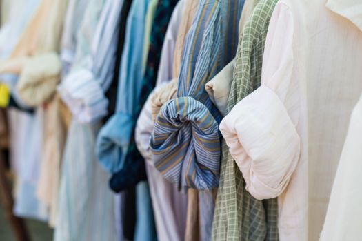 Old shirt hanging on plastic hangers in second hand maket