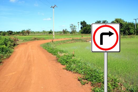 Turn right sign with soil road in countryside