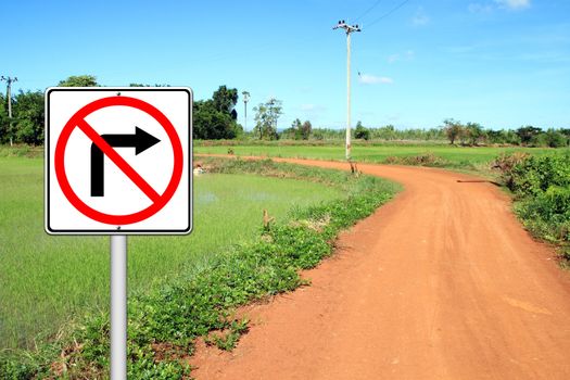 don't turn right sign with a left curved soil road