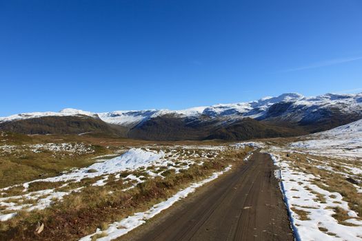 The picture shows the parts of a dirt road that goes over a mountain pass in Norway. It is best accessible by tractor or car with four-wheel drive