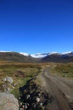 The picture shows the parts of a dirt road that goes over a mountain pass in Norway. It is best accessible by tractor or car with four-wheel drive