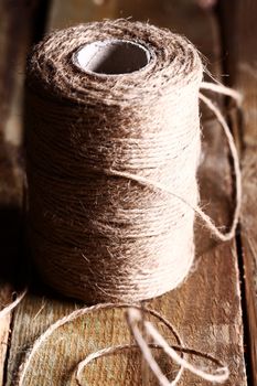 Artistic image of spool of thread over wooden surface