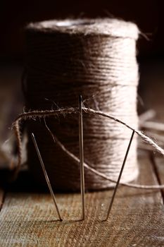 Artistic image of spool of thread and needle over wooden surface