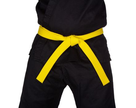 Karate yellow belt tied around marital artists torso wearing black dojo GI's.