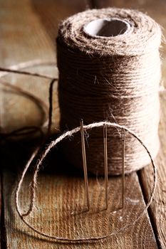 Artistic image of spool of thread and needle over wooden surface