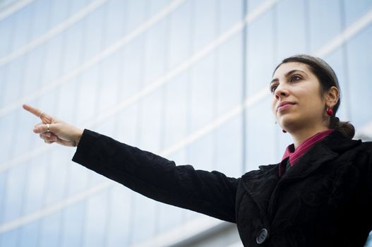 business girl pointing in front of a modern building