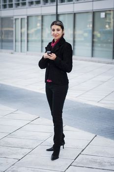 smiling business girl on the phone in front of a modern building