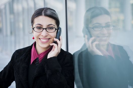 smiling business girl on the phone in front of modern building