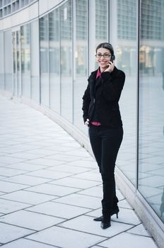 smiling business girl on the phone in front of modern building