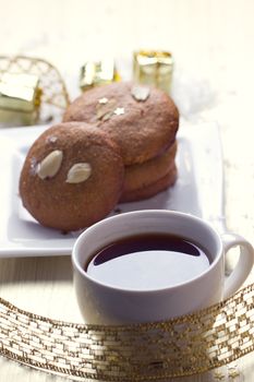 Cookies with nuts and a cup of tea on a background of Christmas gifts