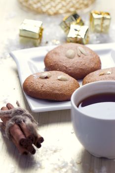 Cookies with nuts and a cup of tea on a background of Christmas gifts