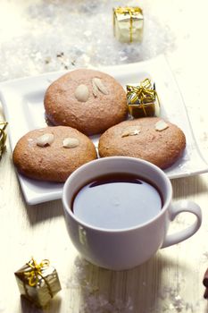 Cookies with nuts and a cup of tea on a background of Christmas gifts