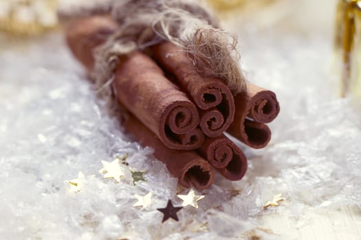 bunch of cinnamon sticks tied with a thread lies on the snow