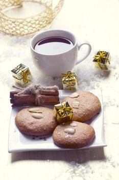 Cookies with nuts and a cup of tea on a background of Christmas gifts