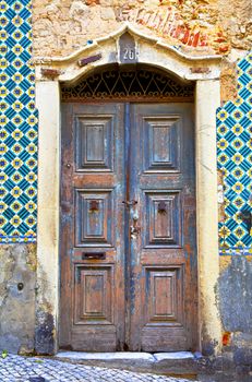 Old wooden door in Portugal. Wall of traditional Portuguese tiles