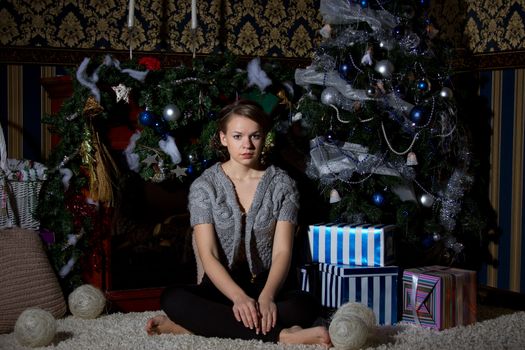 Beautiful girl with the present near the Christmas tree