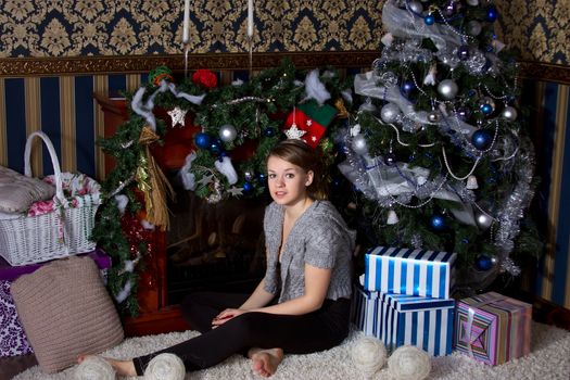 Beautiful girl with the present near the Christmas tree