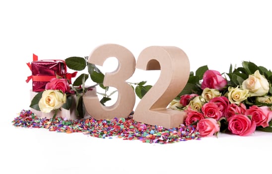 Number of age in a colorful studio setting with fresh roses on a bottom of confetti