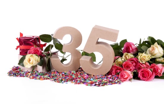 Number of age in a colorful studio setting with fresh roses on a bottom of confetti