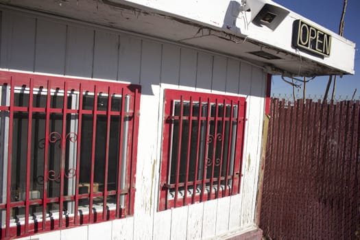 A business with open sign and red security bars