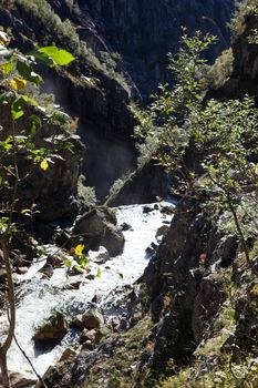 A waterfall in a beautiful autumn hills, with snow on the mountain peaks and beautiful colors of the trees