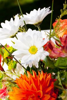 White, orange, and green wedding flower arrangements with burlap as the centerpieces for table settings at an outdoor reception.